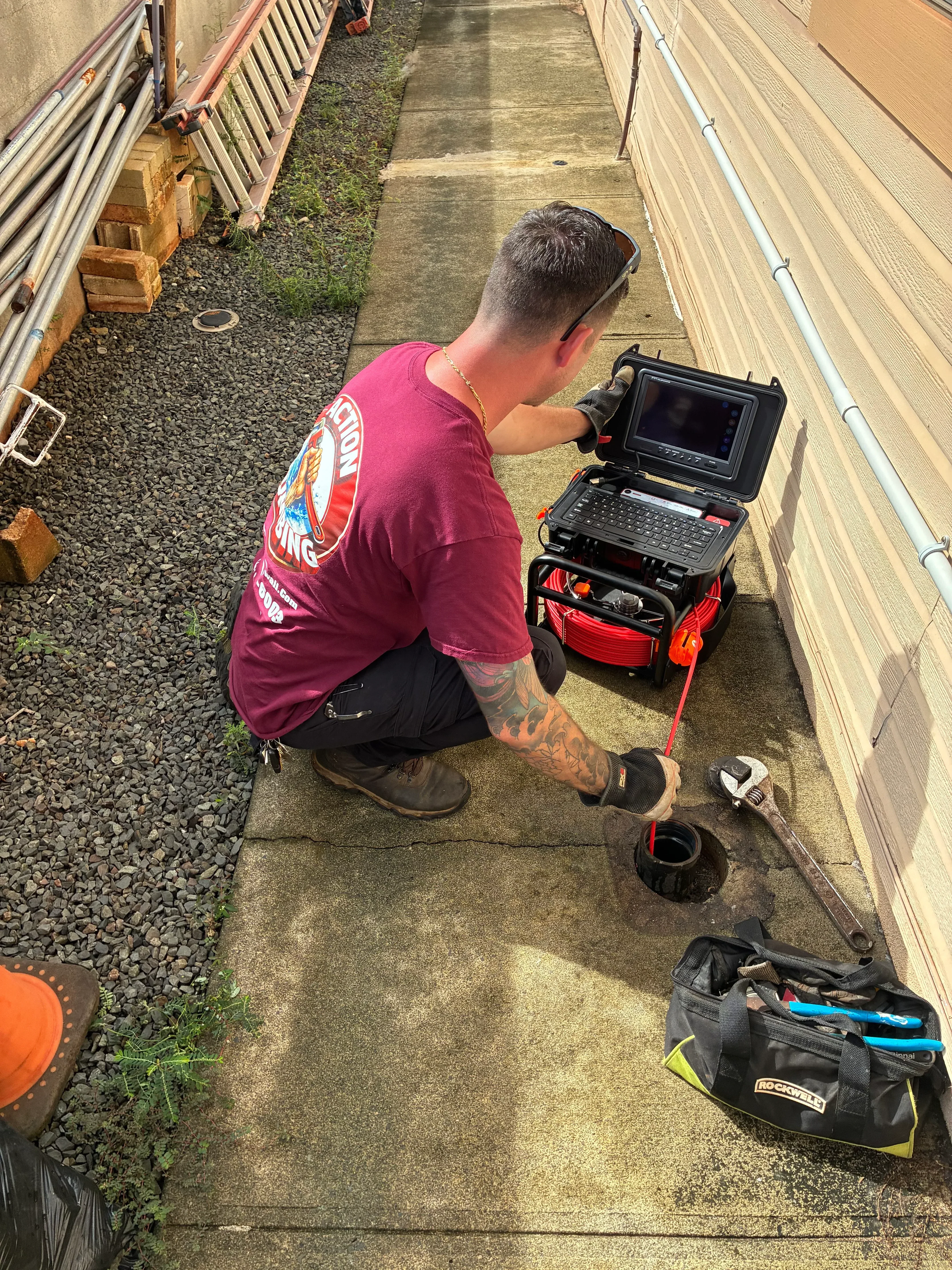 Plumber operating sewer camera equipment with monitor and motorized cable reel for underground line inspection