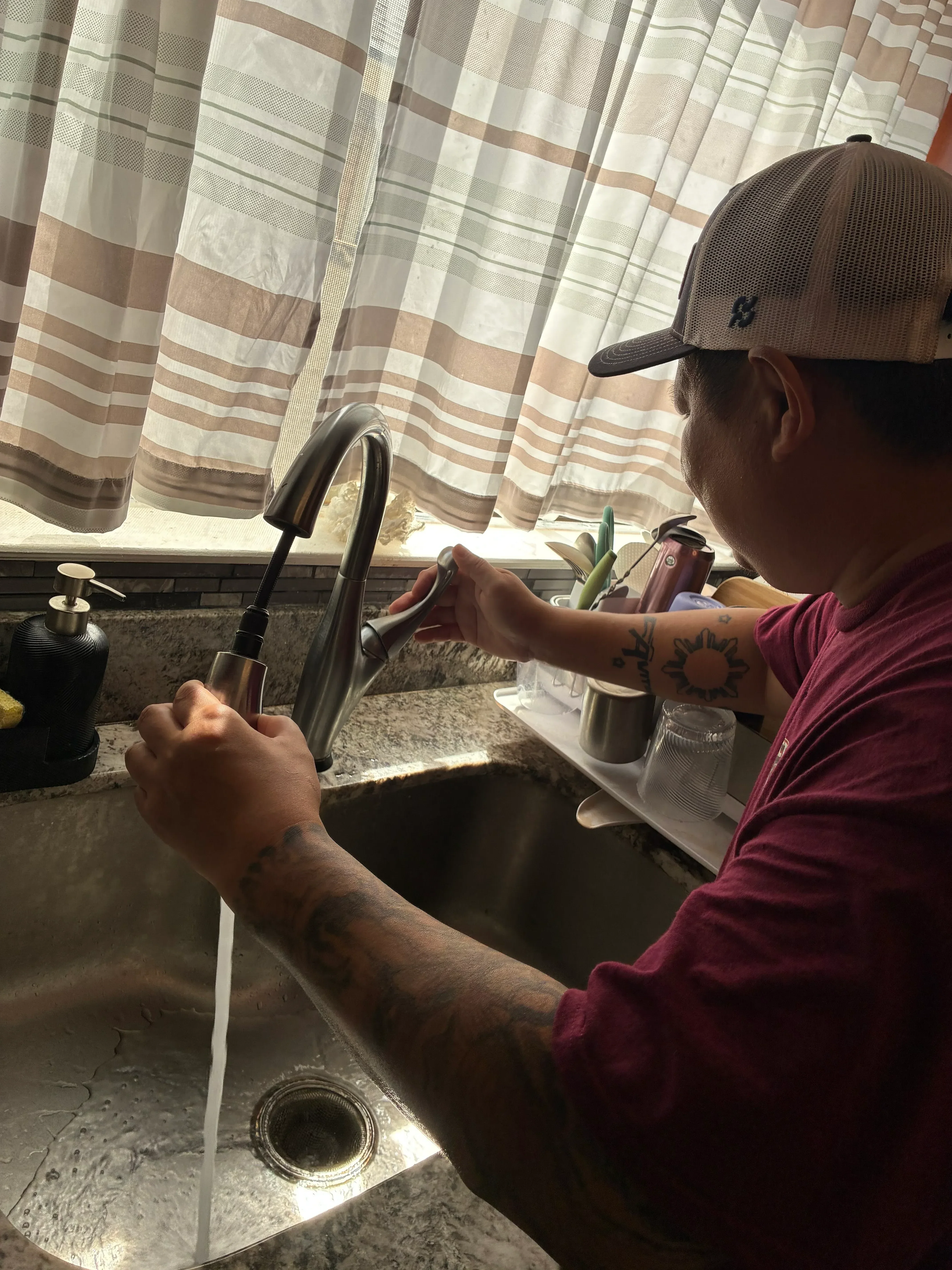 Plumber installing stainless steel kitchen sink with faucet and drain connections