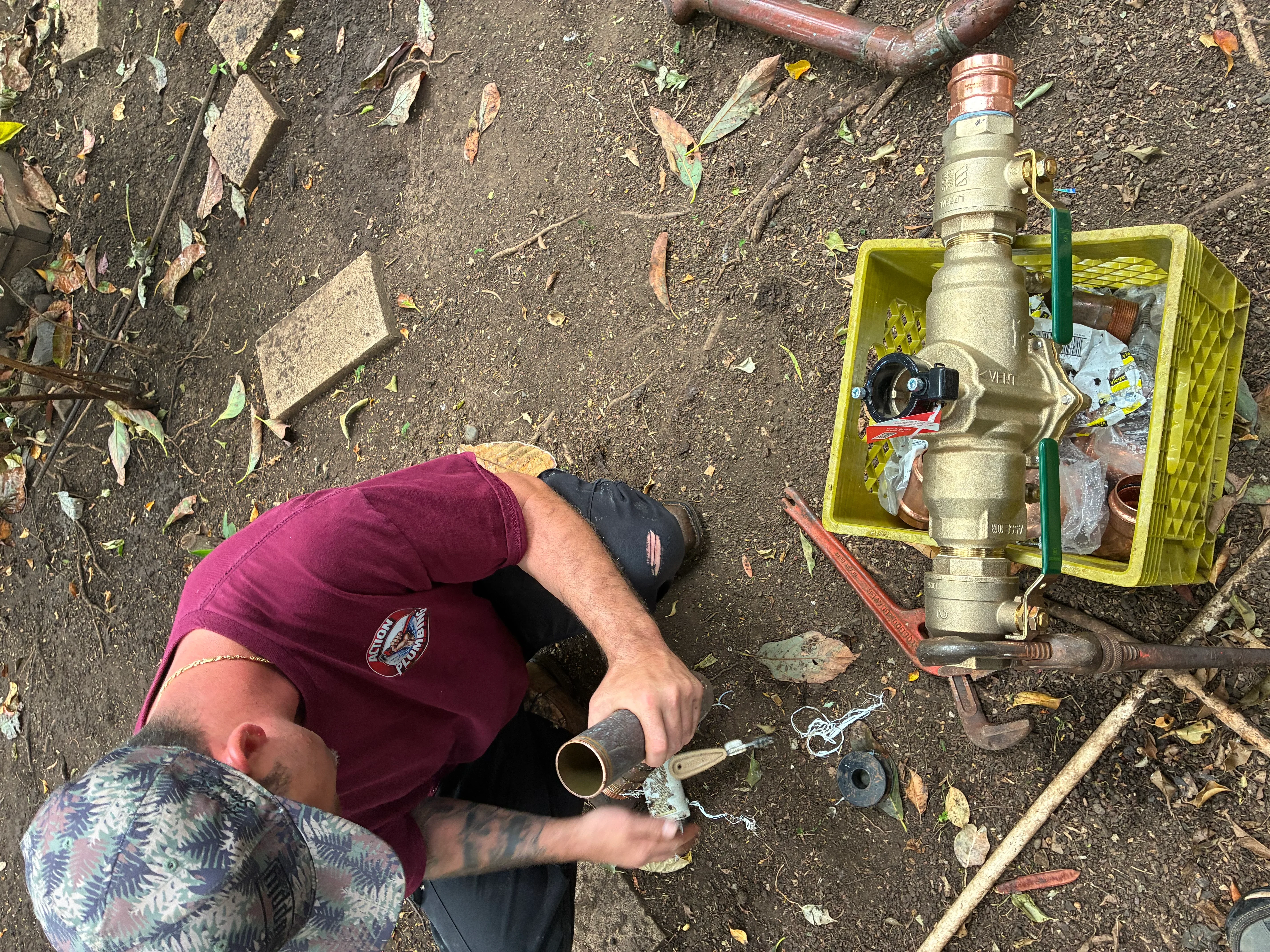 Plumber installing brass water valve with copper pipe connections and organized tools