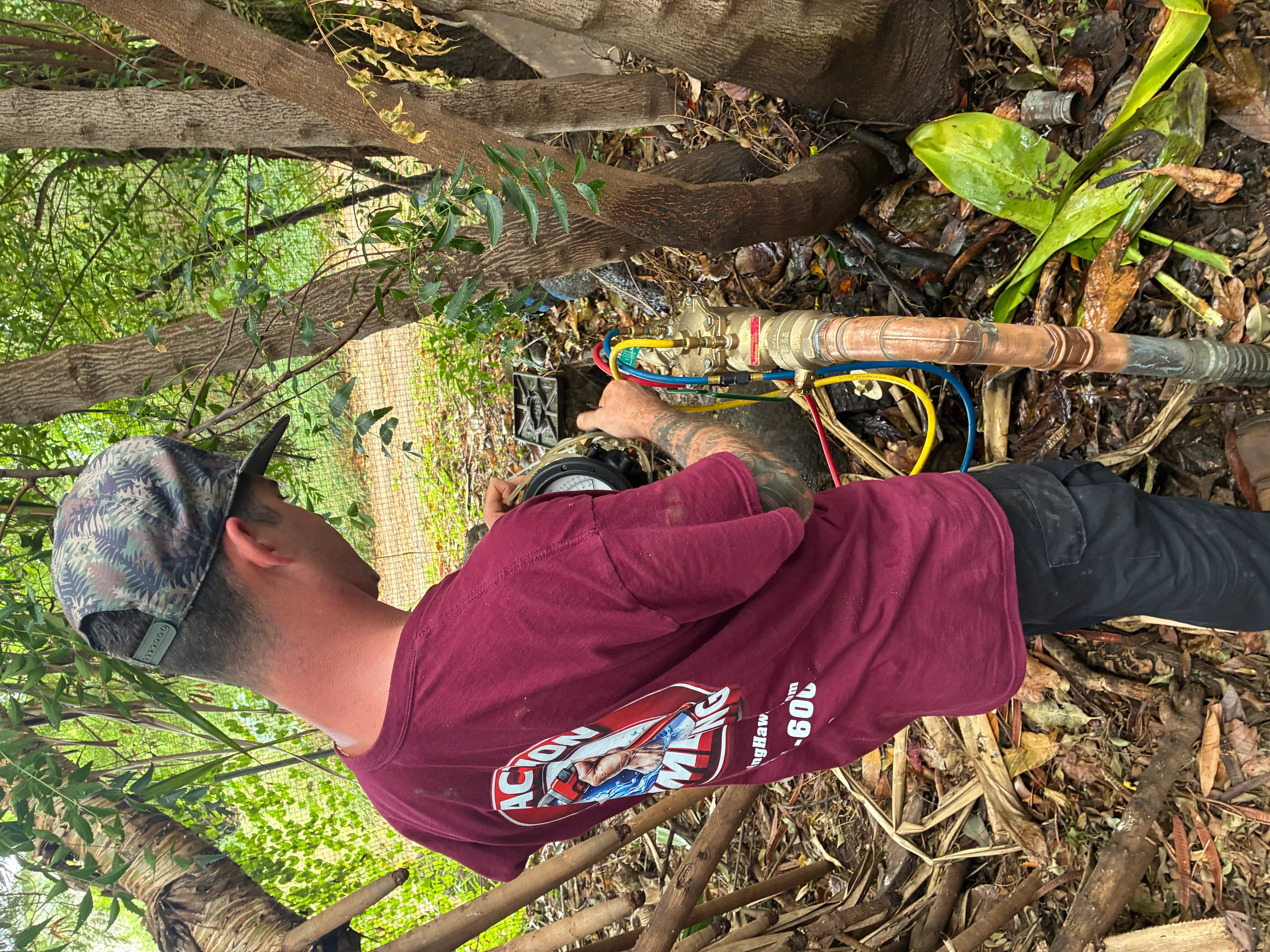 Technician installing copper plumbing line with color-coded wires and brass fittings outdoors