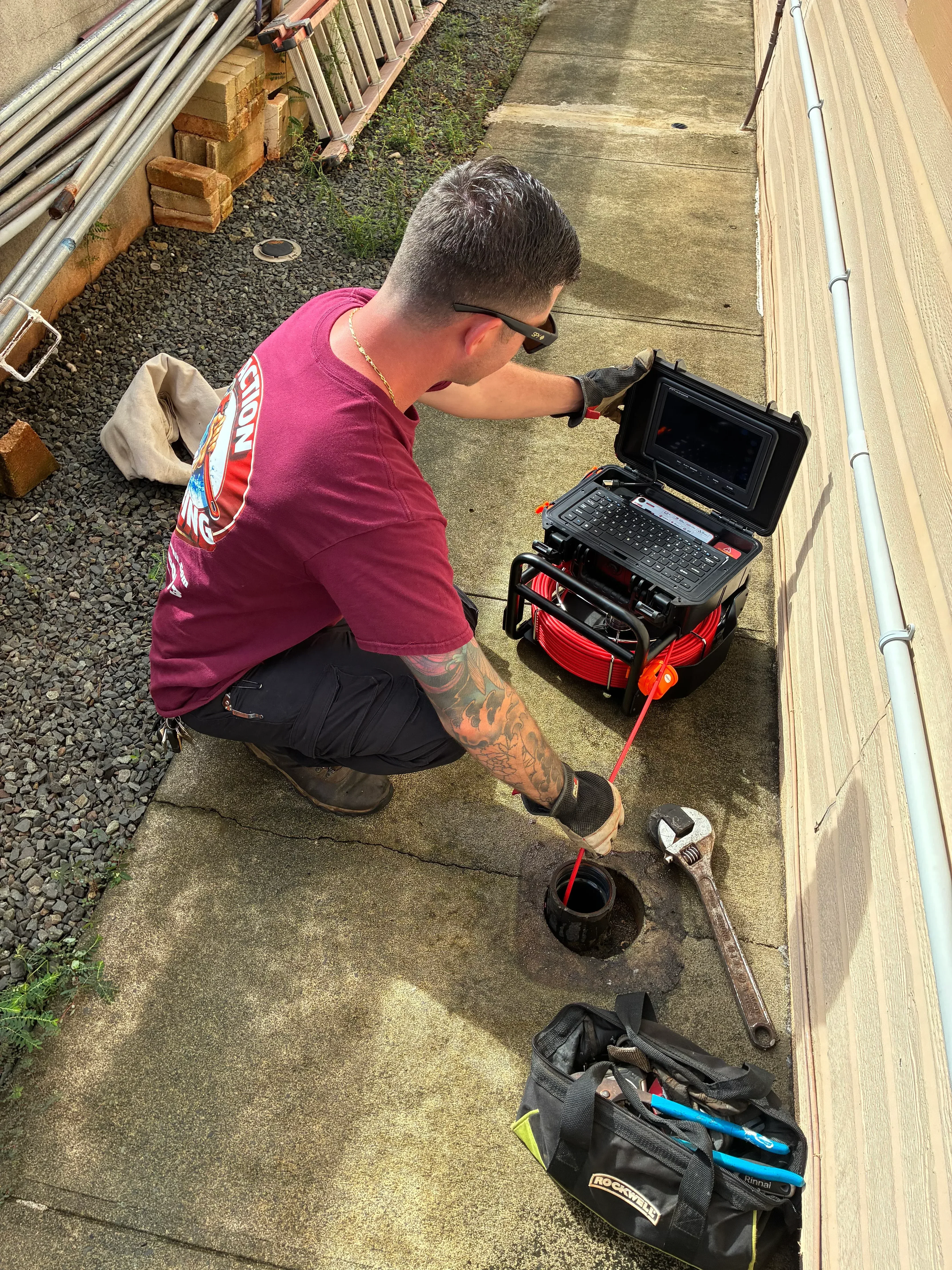 Plumber performing sewer line video inspection with camera equipment and generator at cleanout access point