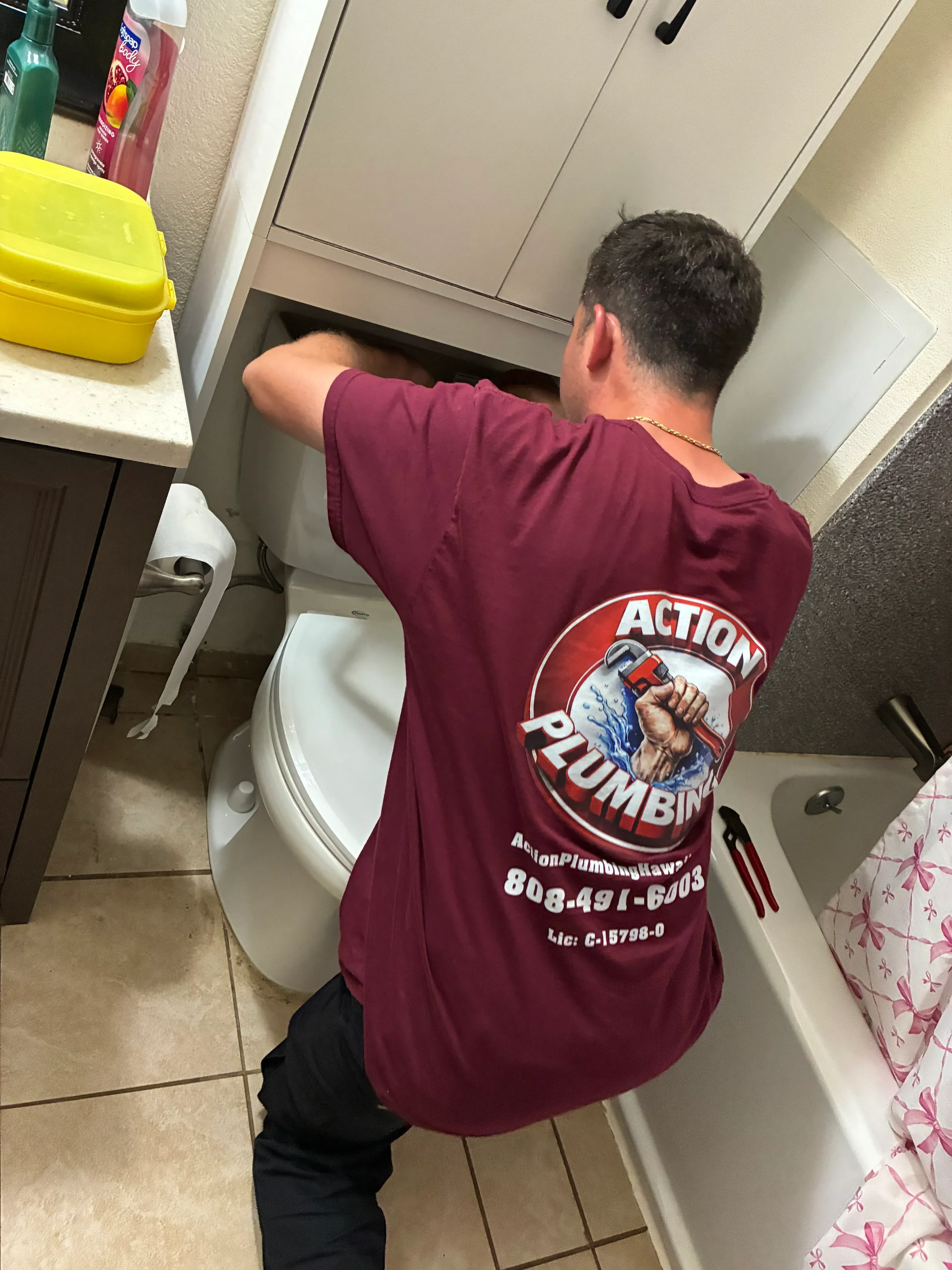 Plumber installing white ceramic toilet in residential bathroom with tile flooring