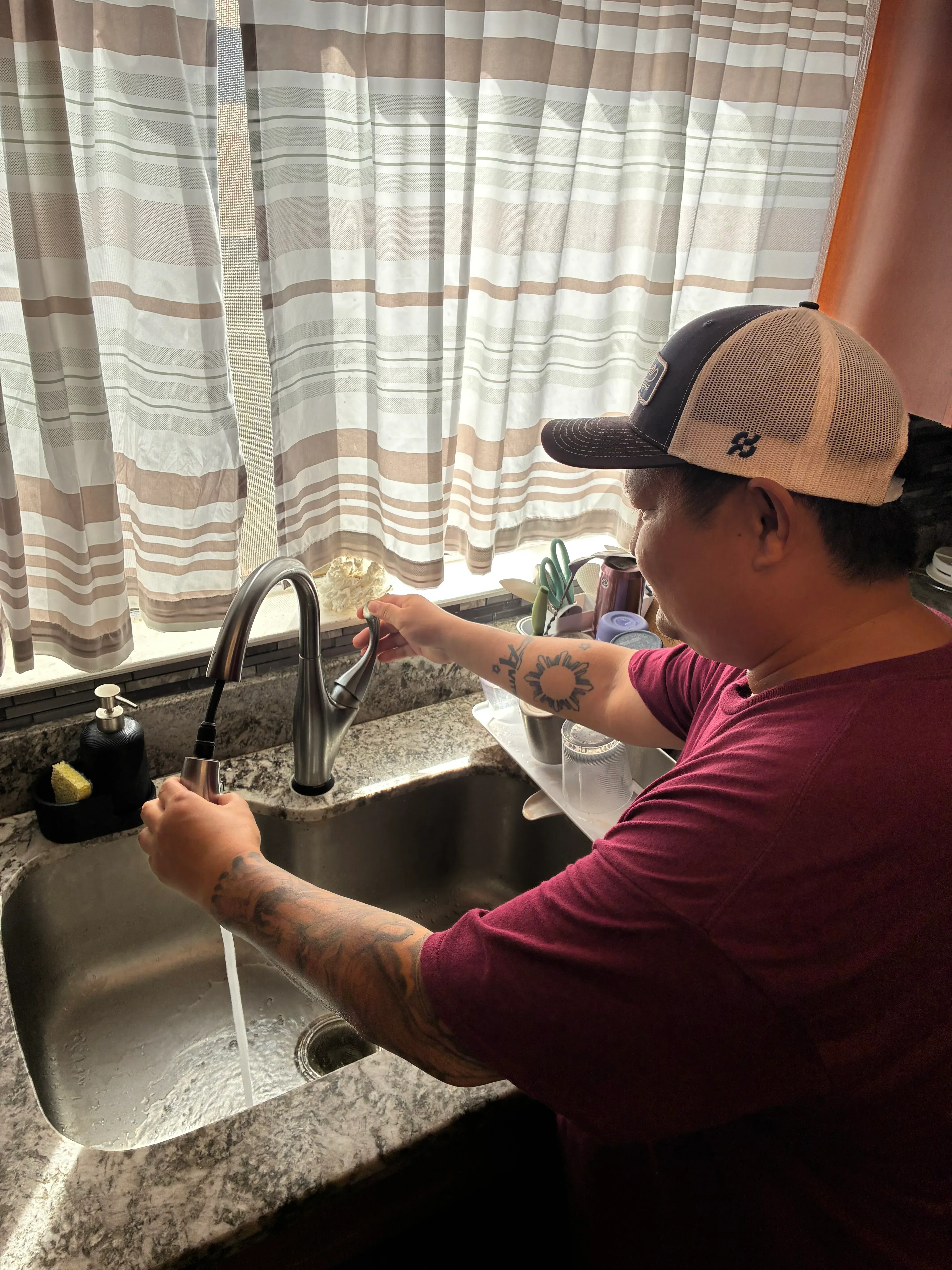 Plumber installing sink supply lines and drain connections under bathroom vanity