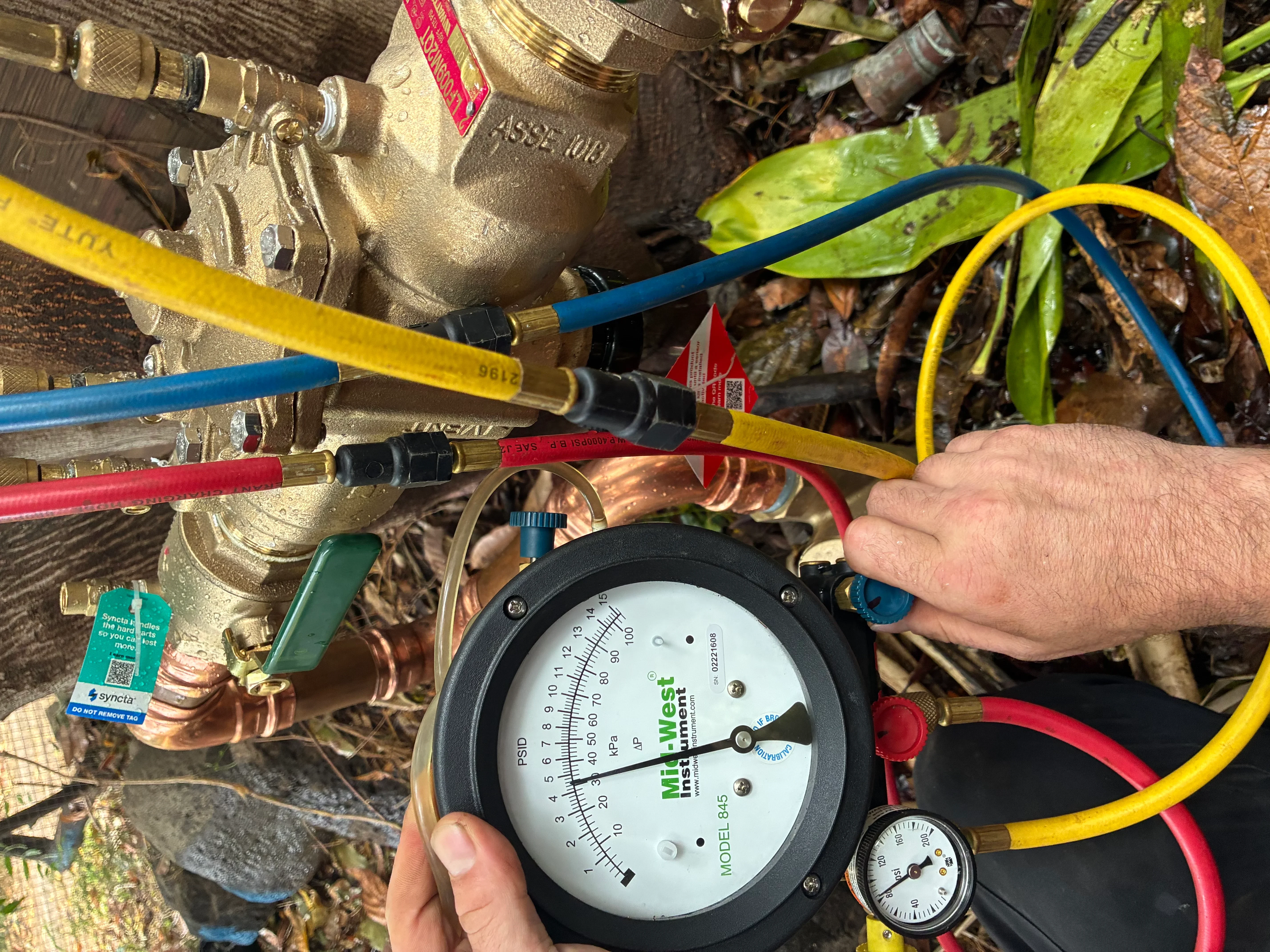 HVAC pressure gauge test with refrigerant lines and brass fittings during system diagnostics